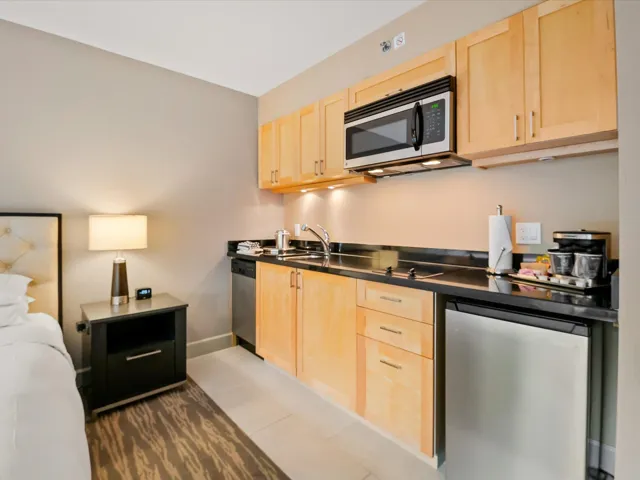 Kitchen with light brown cabinetry, stainless steel appliances, light tile patterned flooring, and dark countertops
