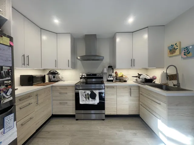 Kitchen featuring appliances with stainless steel finishes, wall chimney range hood, light wood-type flooring, and light brown cabinets