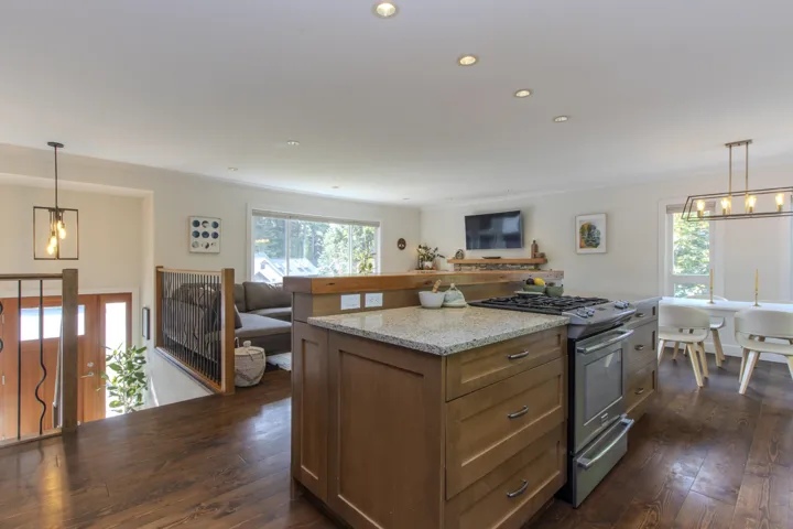 Kitchen featuring decorative light fixtures, stainless steel gas range, light stone countertops, brown cabinets, and recessed lighting