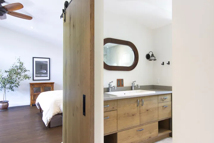 Ensuite bathroom featuring vanity, vaulted ceiling, dark wood-type flooring, and ceiling fan