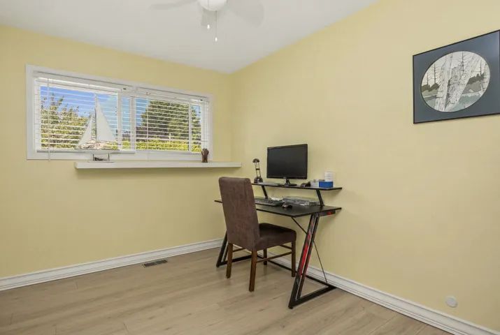 Bright room featuring a wide window with horizontal blinds, wood-finish flooring, and a white ceiling fan
