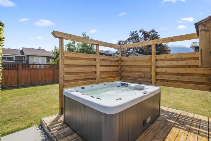 Private backyard featuring a built-in spa, wood privacy screen, and an expansive lawn area