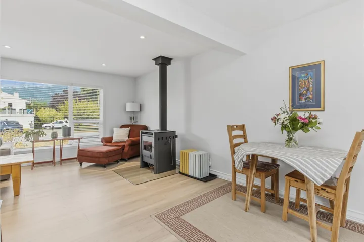 Open-concept living area featuring light wood-finish flooring, recessed lighting, a modern wood-burning stove, and expansive windows