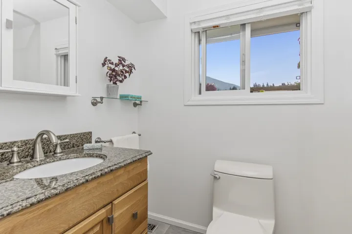 Bathroom featuring a light wood-finish vanity with a granite countertop, undermount sink, and brushed nickel fixtures