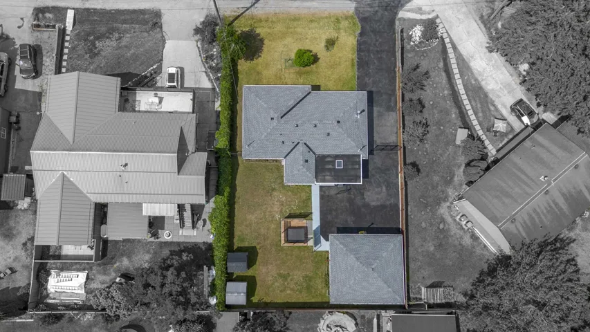 Manicured green lawn surrounding a single-story residence with a gray shingle roof