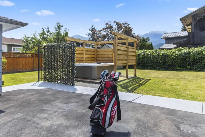 Outdoor spa area featuring a wooden pergola, privacy fence with foliage, and a grey spa unit