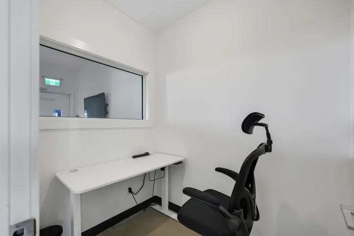 Compact office space featuring a white desk with integrated power outlets, a frosted privacy window, and a light-colored flooring