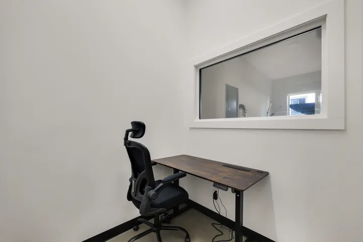 Interior room featuring a large, horizontally oriented interior window, light-colored walls, dark baseboards, and light-colored flooring