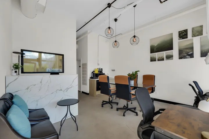Open concept space featuring high ceilings with exposed conduit, track lighting, and spherical pendant lights