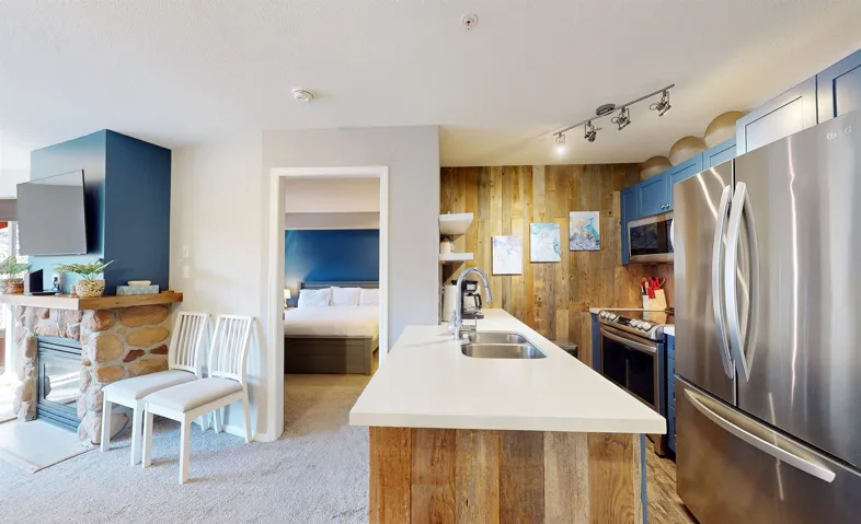 Kitchen featuring light colored carpet, light countertops, stainless steel appliances, wood walls, and a sink