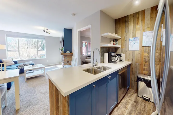 Kitchen featuring open shelves, appliances with stainless steel finishes, a sink, wooden walls, and blue cabinets