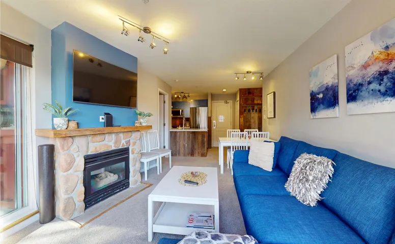 Living room with rail lighting, carpet, and a stone fireplace