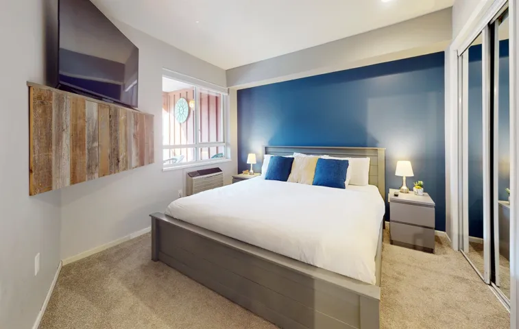 Carpeted bedroom featuring a wall mounted AC and baseboards