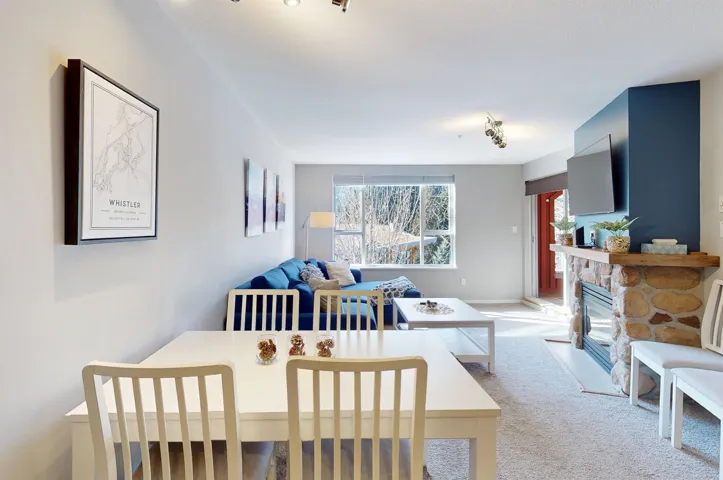 Dining space with light carpet, a fireplace, and track lighting
