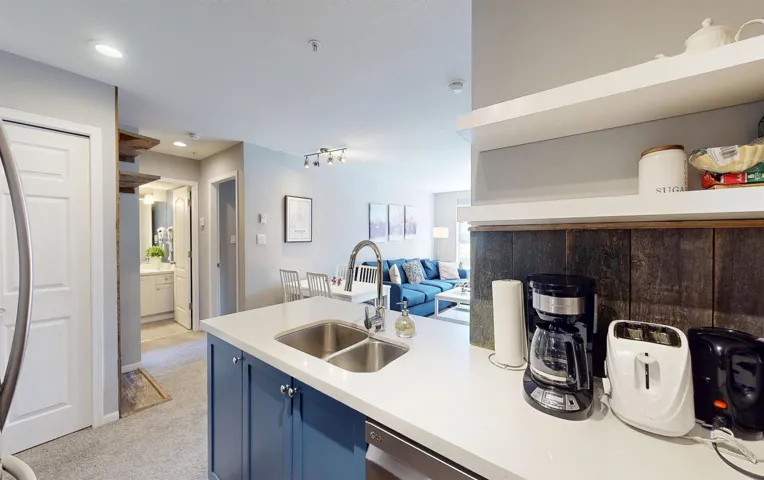 Kitchen featuring light countertops, open floor plan, light carpet, a sink, and blue cabinets