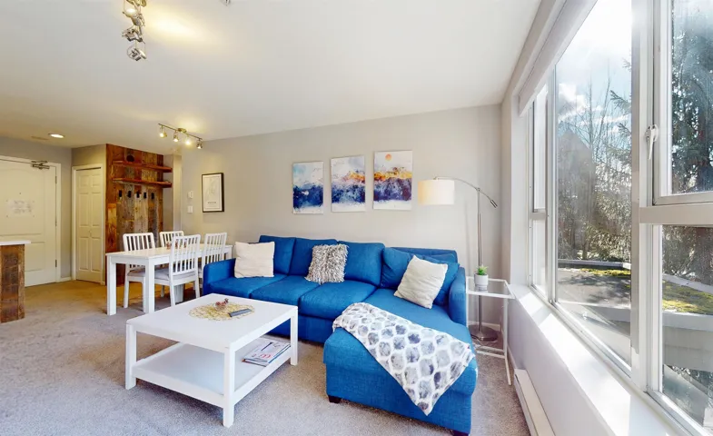 Living area featuring a baseboard radiator, plenty of natural light, carpet flooring, and rail lighting