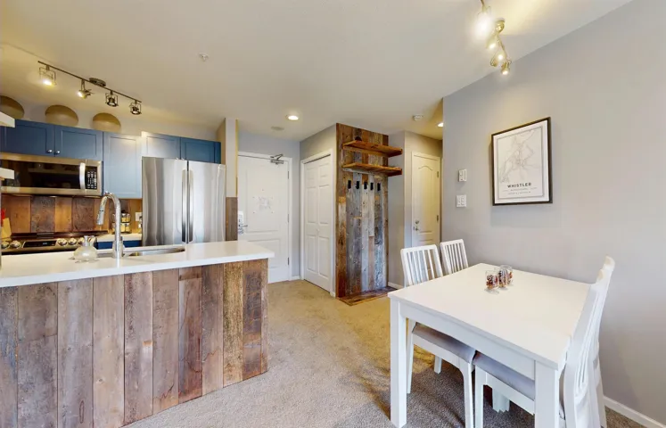 Kitchen featuring light carpet, blue cabinets, stainless steel appliances, light countertops, and a sink