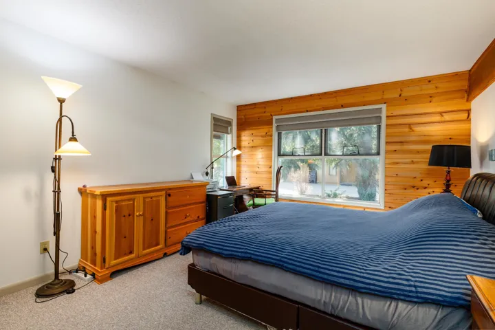 Wood-paneled accent wall featuring a large window with roller shades