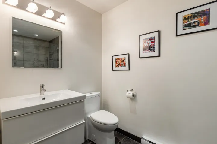 Bathroom featuring a white floating vanity with an integrated sink, a contemporary toilet, and a vanity light bar with frosted glass shades