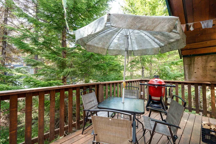 Wood deck with natural wood railings, surrounded by mature evergreen trees
