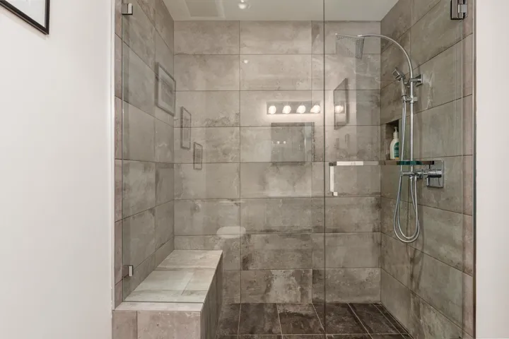Frameless glass shower enclosure featuring large format tile walls and flooring