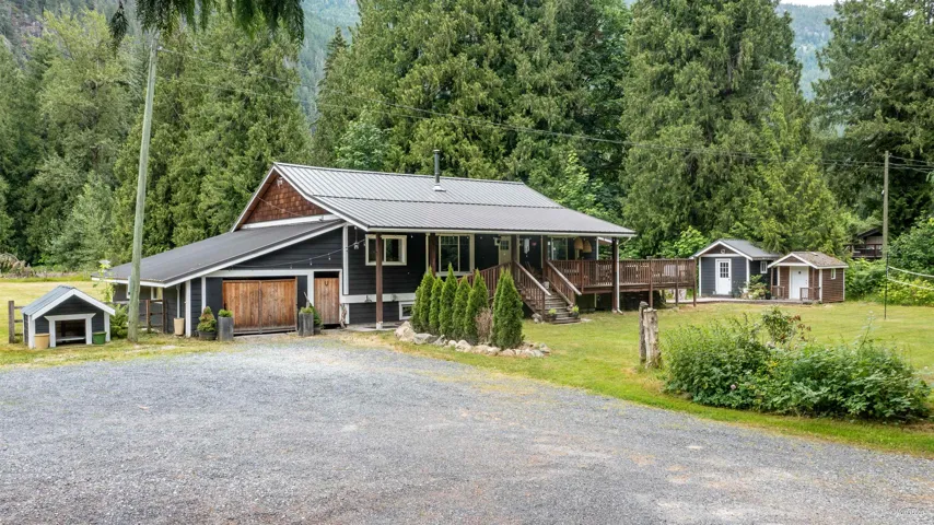 View of front of house with a metal roof, driveway, a front yard, and a storage shed