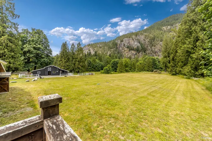 View of green lawn with a mountain view, a view of trees, and an outdoor structure