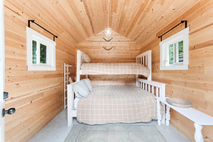 Bedroom featuring wood walls, wooden ceiling, and light tile patterned floors