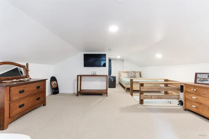 Bedroom featuring lofted ceiling and light carpet