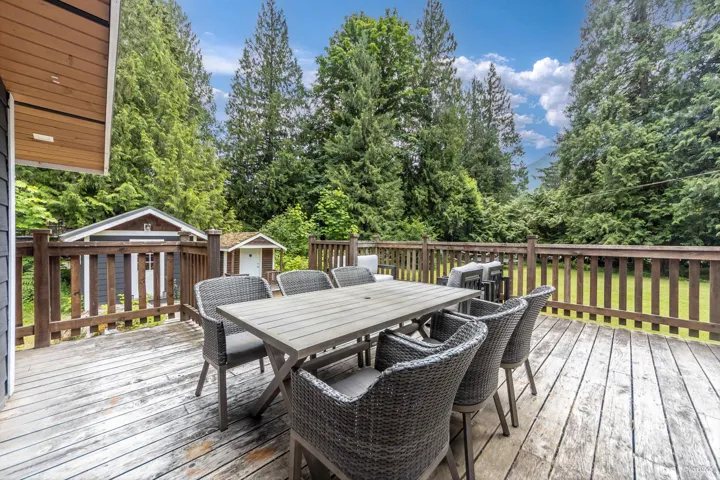 Wooden deck with a storage unit, outdoor dining space, and view of scattered trees