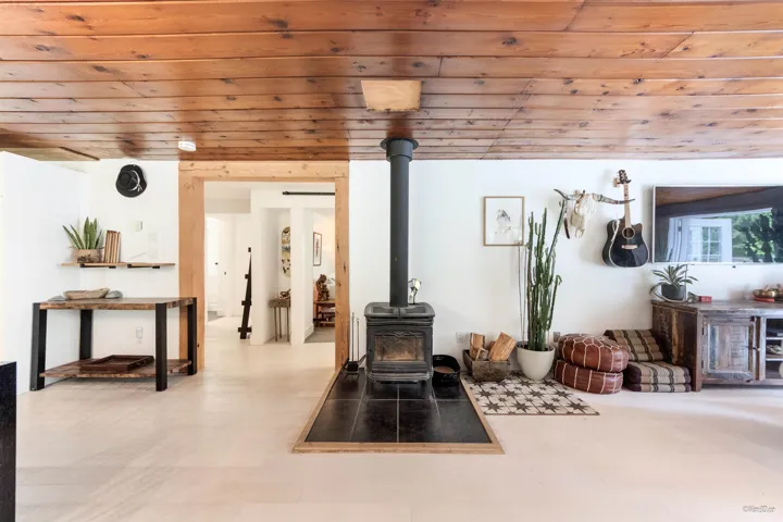 Living area with a wood stove, wooden ceiling, and tile patterned floors