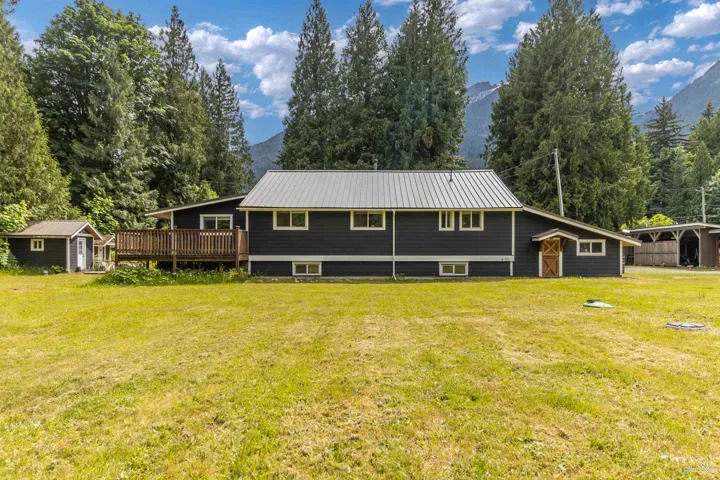 Rear view of house with a shed, a lawn, a metal roof, and a mountain view