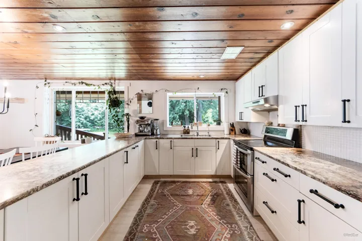 Kitchen with double oven range, wooden ceiling, white cabinets, tasteful backsplash, and light stone countertops