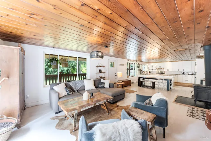 Living area with a wood stove, healthy amount of natural light, and wood ceiling
