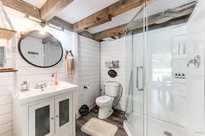 Full bathroom featuring vanity, wood walls, dark wood-style flooring, and a stall shower