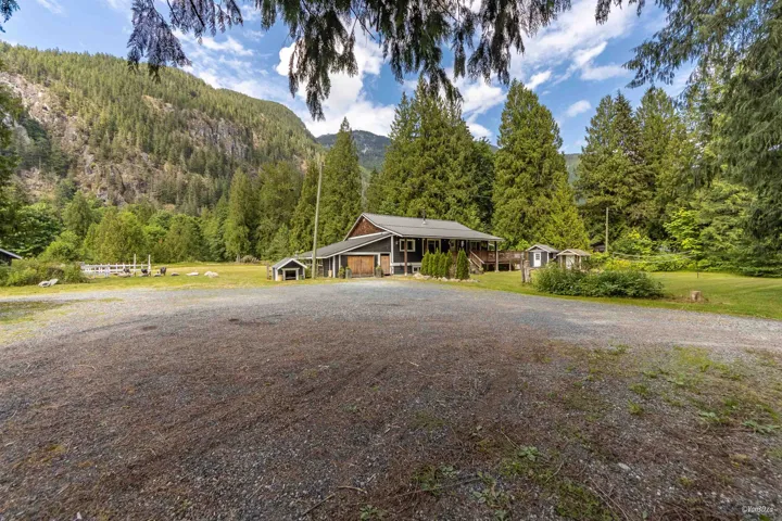 View of front of house featuring a mountain view, driveway, a front yard, and a forest view