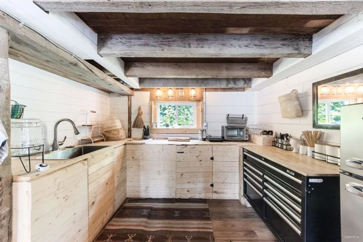Kitchen with freestanding refrigerator, wooden walls, dark wood-style flooring, and butcher block countertops