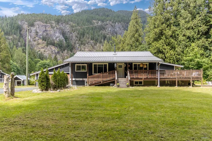 View of front facade featuring a porch, a view of trees, a front lawn, a mountain view, and a standing seam roof