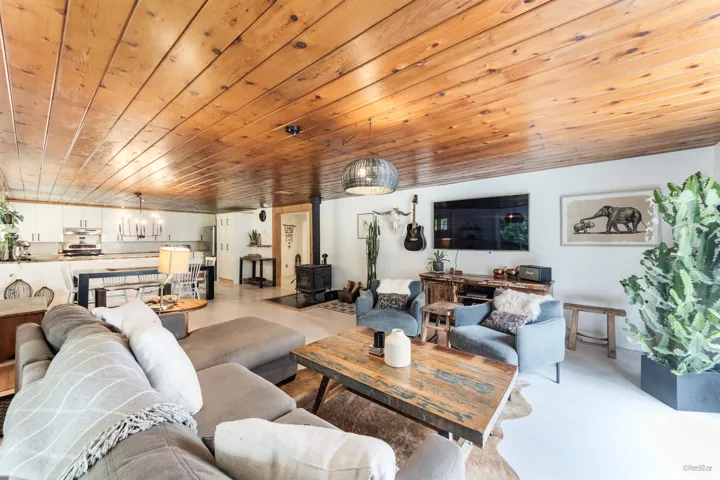 Living area with wood ceiling, a wood stove, and finished concrete flooring