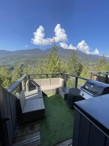 Balcony with a wooded view, outdoor lounge area, a grill, and a deck with mountain view