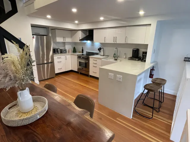Kitchen featuring Douglas Fir flooring, white cabinets, a breakfast bar area, tasteful backsplash, and recessed lighting.