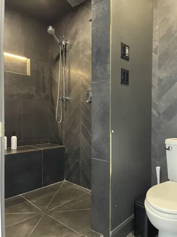 Full bath with tiled shower and toilet