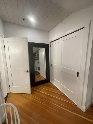 Hall with lofted ceiling, wood finished floors, and recessed lighting
