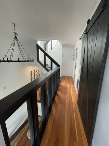 Hall with a barn door, light wood-type flooring, and stairs