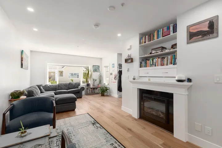Living area featuring light wood-style floors, recessed lighting, and a glass covered fireplace
