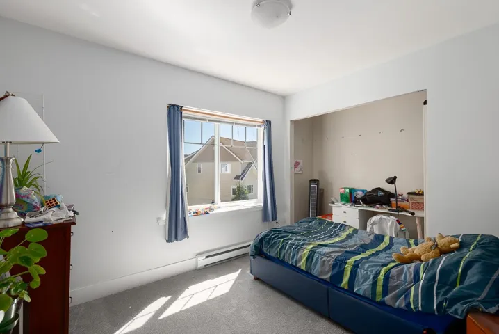 Bedroom with carpet flooring and a baseboard heating unit