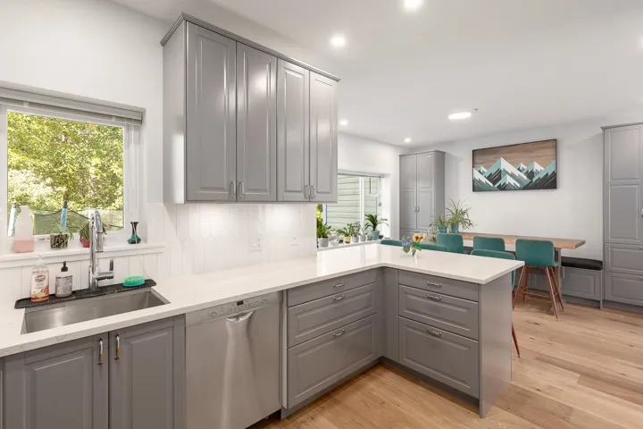 Kitchen featuring gray cabinetry, a peninsula, stainless steel dishwasher, and recessed lighting