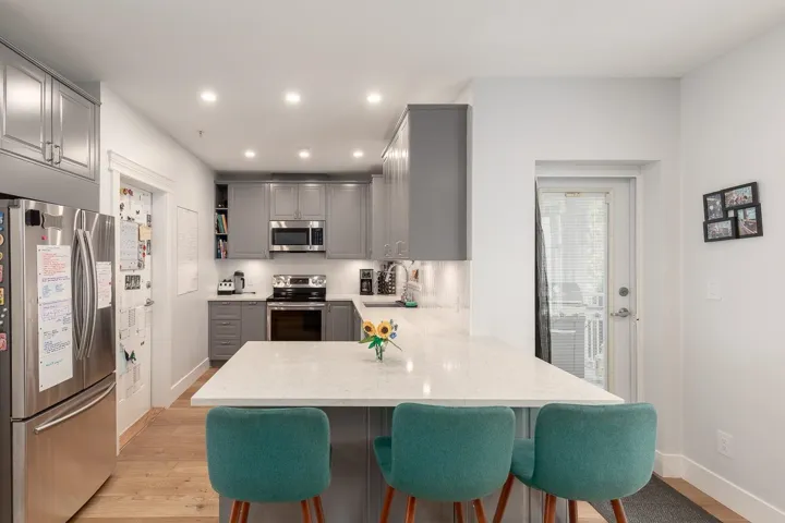 Kitchen with gray cabinets, stainless steel appliances, a peninsula, light wood-style flooring, and recessed lighting