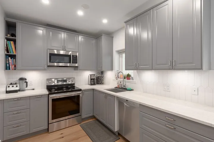 Kitchen featuring gray cabinetry, stainless steel appliances, light wood-type flooring, backsplash, and recessed lighting