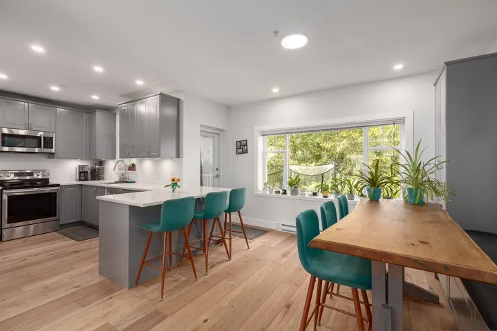 Kitchen with gray cabinetry, appliances with stainless steel finishes, recessed lighting, a kitchen breakfast bar, and a peninsula